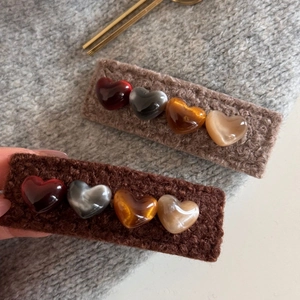 Detail of warm knitted heart hair clips with glossy colorful gems on grey sweater