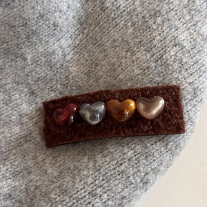 Detail of plush brown hair clip with four shiny resin hearts in vintage warm colors
