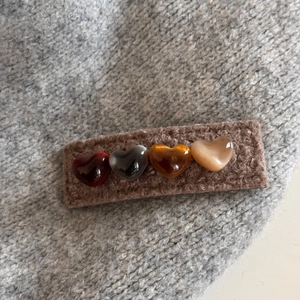 Detail of a brown plush heart hair clip showing its cozy knitted texture and 4 resin beads