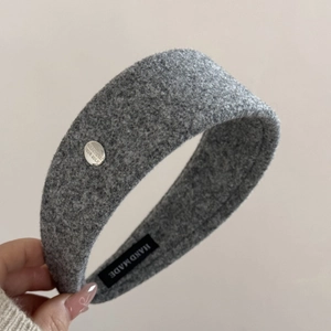 Detail of grey tweed headband showing handmade label and engraved silver metal plate
