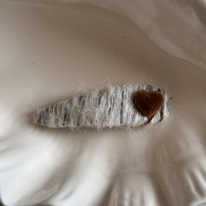 Close-up of heart-shaped knit hair clip with fuzzy wool texture on a ceramic tray