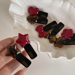 Handmade red acetate heart and star hair clips in elegant shell dish display