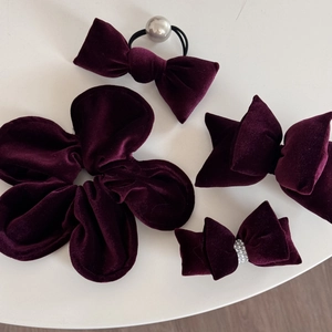 Set of four burgundy velvet hair accessories including bow clips and scrunchies