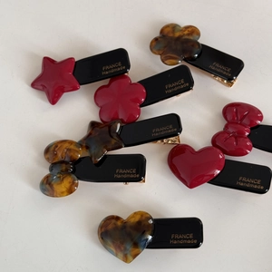Detail showing red and tortoiseshell acetate hair clips with gold France Handmade logo