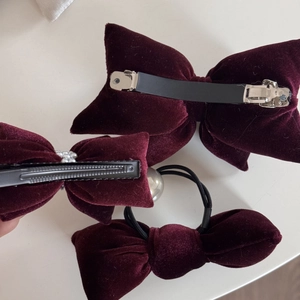 Detailed back view of burgundy velvet bow hair clips and elastic tie with metal fasteners