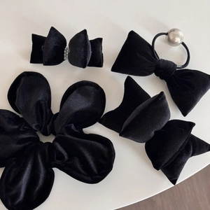 Close-up of black velvet hair accessories including bow hair clips and scrunchies set