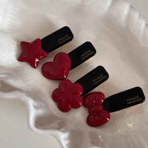 Red acetate hair clip set with star heart flower bow shapes on a white ceramic tray