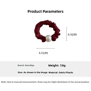 Detail of burgundy ruched elastic scrunchie with large pearl bead accent and 6.5cm diameter