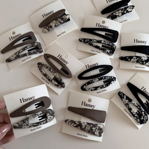 Detailed macro view of assorted floral fabric BB hair clips on branded display cards