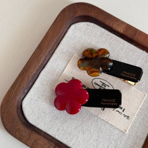 Detail of red and tortoiseshell acetate flower hair clips with gold handmade stamp