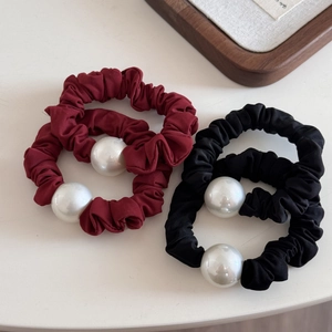 Close-up of black and burgundy fabric hair ties with large decorative white pearls