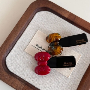 Detailed macro of red and tortoiseshell acetate bow hair clips with gold lettering