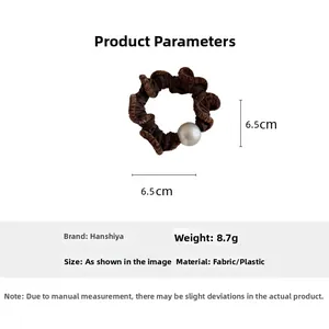 Detailed view of coffee brown ruffled fabric hair scrunchie with elegant white pearl bead