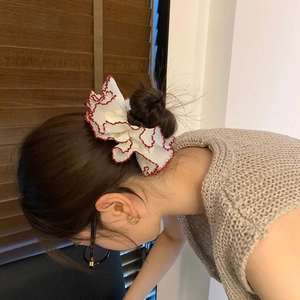 Detail showing white lace scrunchie with red trim on a high bun hairstyle