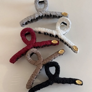 Detail view of woven fabric hair claws in five colors with golden oval egg branding