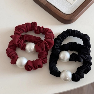 Detail of four high-elasticity hair scrunchies in wine red and black with white pearls