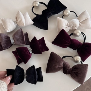 Flat lay of velvet bow hair ties in black, cream, burgundy and brown with pearl accents