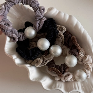 Elegant ruffled fabric hair ties with large pearls in assorted colors on a shell plate