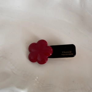 Detail view of the red flower acetate hair clip featuring gold FRANCE Handmade lettering