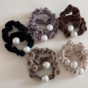 Macro detail of plush velvet hair scrunchies with large pearl beads in assorted colors
