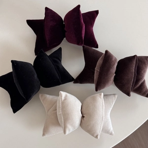 Detail view of four velvet bow clips in purple, black, coffee, and beige colors