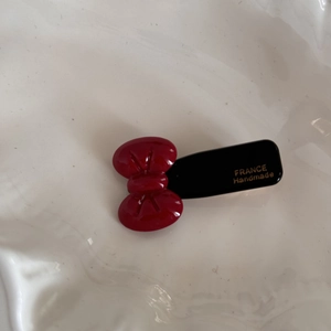 Detailed macro view of a red handmade bow hair clip with gold France lettering on black base