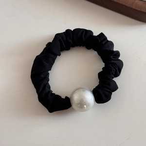 Detail of black pleated scrunchie with a large white pearl bead for hair styling