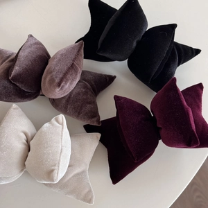 Macro detail of four velvet bow hair clips in black, coffee, burgundy and cream white