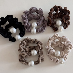 Detail view of five plush pearl hair scrunchies in neutral tones on white background