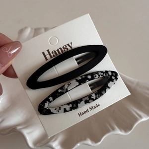 Detail of handmade oval hair clips set with classic black and cow pattern fabric wrapping