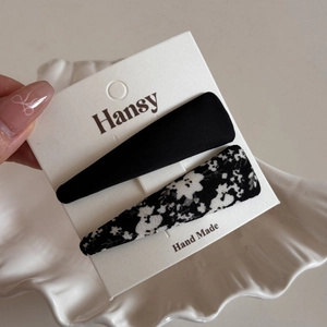 Detail of floral and solid fabric snap hair clips on a white display card in hand