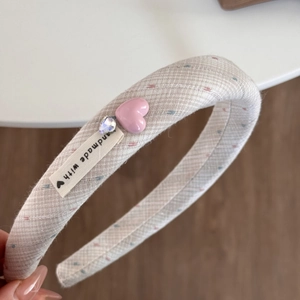 Détail du pendentif cœur rose et dentelle sur un serre-tête en tissu à pois colorés