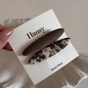 Detail of handmade fabric hair clips featuring brown solid color and floral patterns