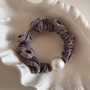 Detail of grey-purple velvet scrunchie with white pearl on a ceramic shell tray