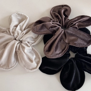 Detail view of velvet floral scrunchies in cream, brown, and black with fine piped edges