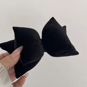 Detail shot of the plush black velvet bow hairpin showing soft fabric texture