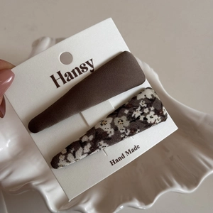 Detail view of floral and solid fabric snap hair clips on a branded display card