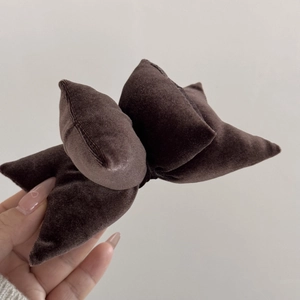 Close-up of a plush dark brown velvet bow hair clip with a layered texture design