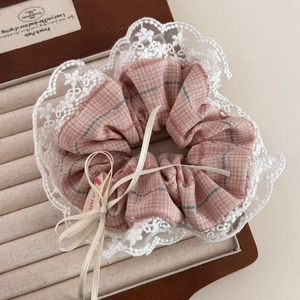 Détail du chouchou à carreaux roses avec bordure en dentelle blanche et étiquette