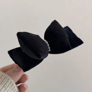 Detail of vintage black velvet bow hair clip with central pearl bead decoration