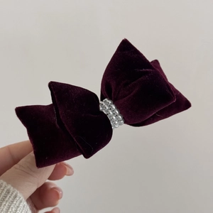 Close-up of a burgundy velvet bow hair clip with three rows of elegant white pearls