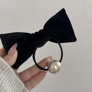 Detail of a black velvet bow hair tie with a polished silver metallic bead decoration