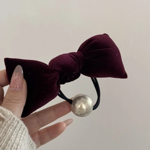 Macro detail of wine red velvet bow hair clip with polished silver bead and elastic band