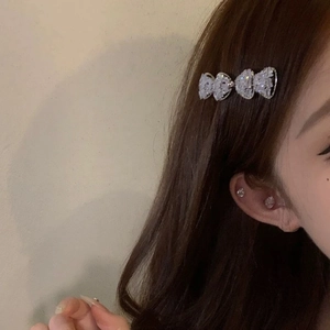 Vue macro d'une barrette à nœud strass étincelant portée sur le côté par un modèle