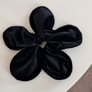 Detail of a handmade black velvet flower scrunchie with soft texture and floral petals