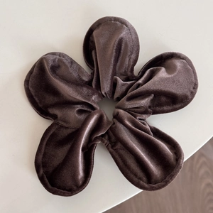 Detailed top view of a brown velvet flower hair clip with thick fabric texture on white surface