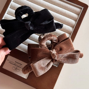 Detail view of premium velvet bow hair claws in black and brown on a jewelry tray