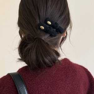 Elegante molletta per capelli in peluche nero con fibbia dorata su uno chignon basso