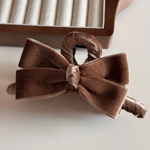Detailed texture of a brown velvet bow hair claw clip on a wooden display tray