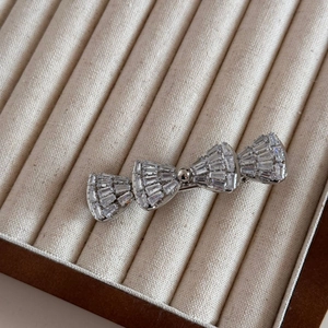 Détail d'une barrette noeud en strass avec zircons baguette sur un plateau de velours